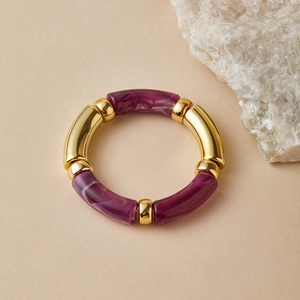 Detail of purple marble resin beads and polished golden metal tubes on a beaded bracelet