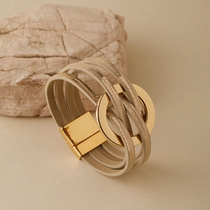 Détail d'un bracelet multicouche en cuir beige avec fermoir magnétique doré élégant
