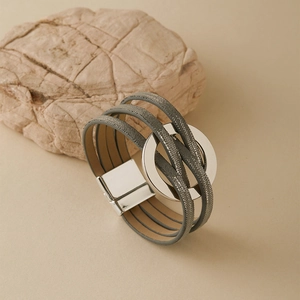 Détail d'un bracelet bohème multicouche avec lanières grises et boucle ronde en métal argent