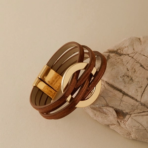 Détail d'un bracelet bohème multicouche en cuir marron avec anneaux dorés et fermoir magnétique