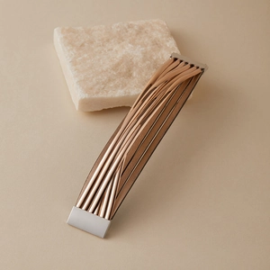 Detail eines mehrlagigen Armbands in Roségold und Leder mit Magnetverschluss im Fokus