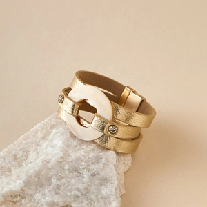 Primer plano de una pulsera multicapa dorada de cuero con anillo de perlas y cierre imán