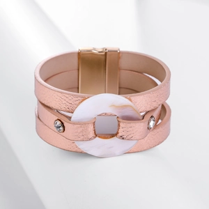 Primer plano de pulsera multicapa de cuero sintético oro rosa con anillo de nácar y cierre magnético