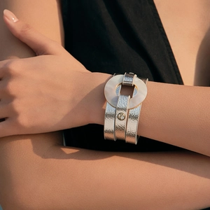 Brazalete ancho de cuero plateado con anillo de resina blanca y detalle de pedrería