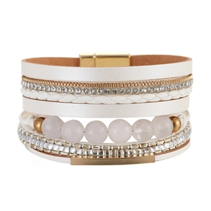 Dettaglio di un bracciale boho multistrato con perle di cristallo e chiusura magnetica oro