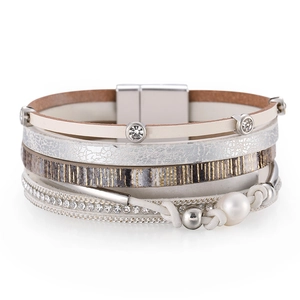 Détail macro d'un bracelet multi-rangs en cuir avec perles, strass et fermoir magnétique