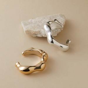 Detailweergave van onregelmatige goud en zilveren armbanden met vloeibare golftextuur