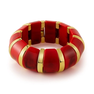 Détail macro de blocs en résine rouge et barres dorées polies sur bracelet élastique