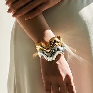 Onregelmatige golvende acryl armbanden in goud en zilver met een hoogglans spiegeleffect