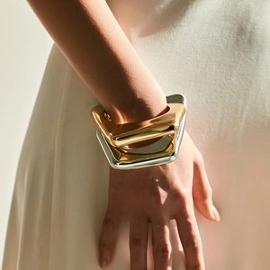 Minimalistische geometrische armband in gepolijst goud en zilver om de pols van een model