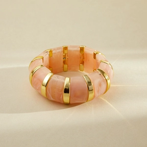 Détail des segments en résine marbrée rose et accents en métal doré sur le bracelet