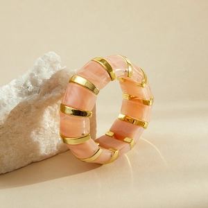 Détail d'un bracelet large en résine marbrée avec séparateurs en métal doré poli