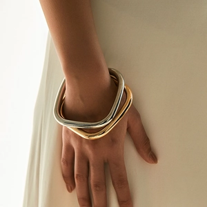 Set van minimalistische vierkante metalen armbanden in gepolijst goud en zilver op model