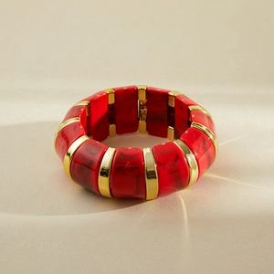 Gros plan d'un bracelet en résine marbrée rouge avec des détails dorés chic