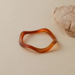 Détail macro du bracelet en résine ambrée au design ondulé irrégulier sur pierre