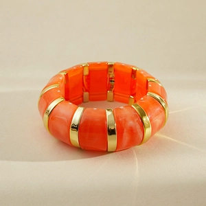 Détail d'un bracelet manchette rétro en résine marbrée orange avec des séparateurs dorés
