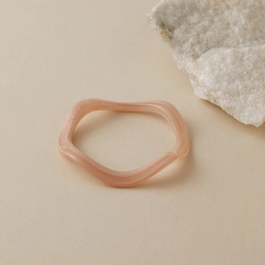Détail d'un bracelet en acrylique pêche ondulé avec texture marbrée sur pierre
