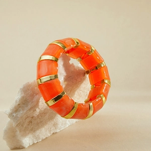 Détail du bracelet extensible avec des pièces en résine orange marbrée et métal doré