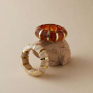 Détail de bracelets rétro en acrylique aux textures ambre et marbre sur une pierre