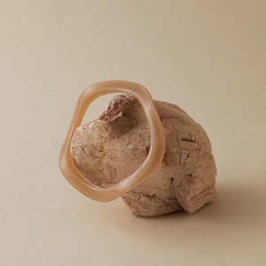 Détail d'un bracelet acrylique aux formes irrégulières rose translucide sur pierre