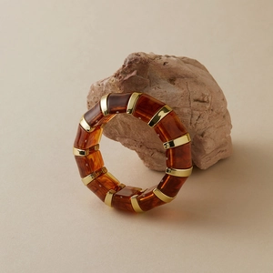 Gros plan d'un bracelet en acrylique ambré avec intercalaires en métal doré