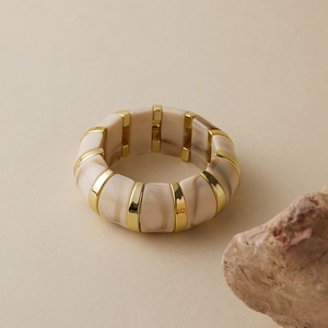 Détail macro du bracelet en résine marbrée crème avec intercalaires dorés sur pierre