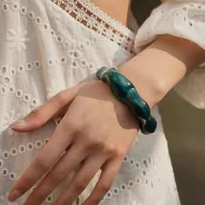 Bracciale in resina acrilica verde scuro con trama ondulata irregolare indossato