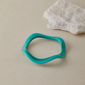 Détail d'un bracelet en acrylique translucide bleu avec texture de vagues irrégulières