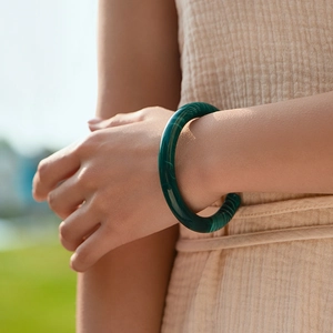 Bracciale rigido minimalista in acrilico verde scuro con trama malachite in ambiente naturale