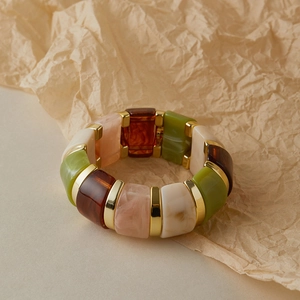 Détail d'un bracelet extensible rétro en acrylique avec entretoises dorées et résine
