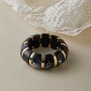 Détails de perles en résine marbrée et anneaux dorés sur le bracelet élastique