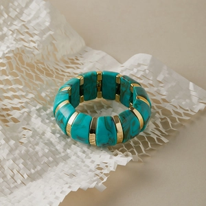 Gros plan détaillé d'un bracelet extensible en résine turquoise marbré avec perles dorées