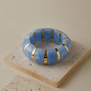 Détail du bracelet élastique en acrylique bleu clair avec maillons en métal doré