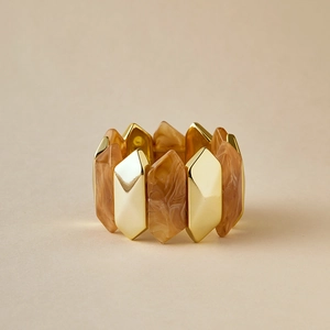 Detalle de brazalete geométrico con eslabones de metal dorado y resina ámbar