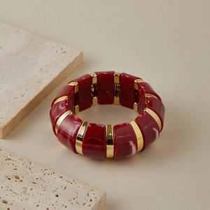 Détail du bracelet élastique en acrylique marbré rouge avec connecteurs dorés