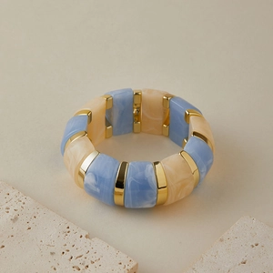 Gros plan d'un large bracelet extensible avec blocs de résine marbrée bleue et or