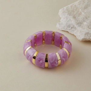 Gros plan du bracelet en acrylique marbré violet avec séparateurs dorés polis élégants