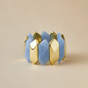 Detalle de pulsera elástica con acrílico jaspeado azul y metal dorado geométrico