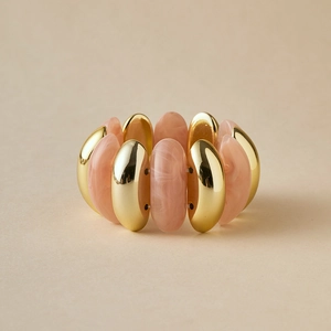 Détail macro du bracelet élastique avec résine marbrée rose et tubes métalliques dorés