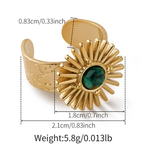 Detailed view of vintage gold ring with green stone and embossed sunburst design