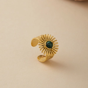 Macro detail of vintage gold adjustable ring with engraved sunburst and green stone