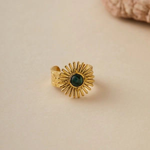 Macro shot of gold bohemian ring with sunray texture and green stone center