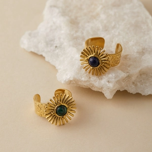 Close-up of vintage gold rings with sunburst design and inlaid blue and green stones