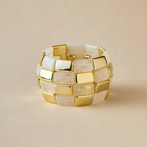 Detail of wide acrylic bangle with alternating gold metal and white marble resin segments
