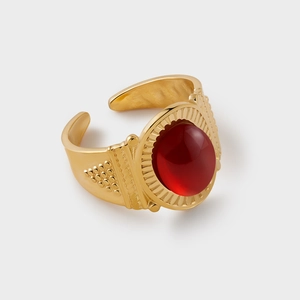Macro detail of vintage gold plated ring featuring red stone and intricate sunburst textures