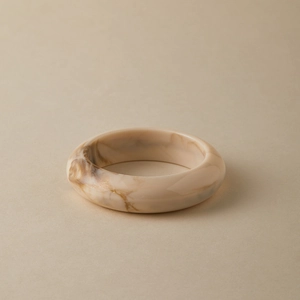 Detail of chunky acrylic bangle featuring a retro marble pattern in beige and brown tones