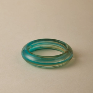 Detail of teal and amber marble pattern on a polished acrylic geometric bangle