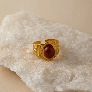 Detailed side view of vintage gold ring with oval red stone and solar pattern on white rock