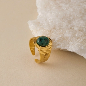 Close-up of vintage gold band ring with oval green turquoise stone and radial engravings