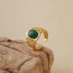 Detailed close-up of retro gold plated turquoise ring on a natural stone base